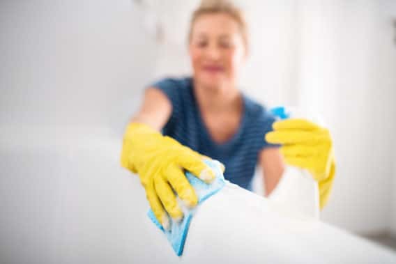 NEAT Senior woman with gloves cleaning bathroom indoors at home.